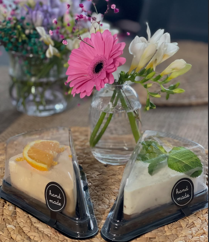 Two handmade cheesecake slices in packaging with hand-made stickers